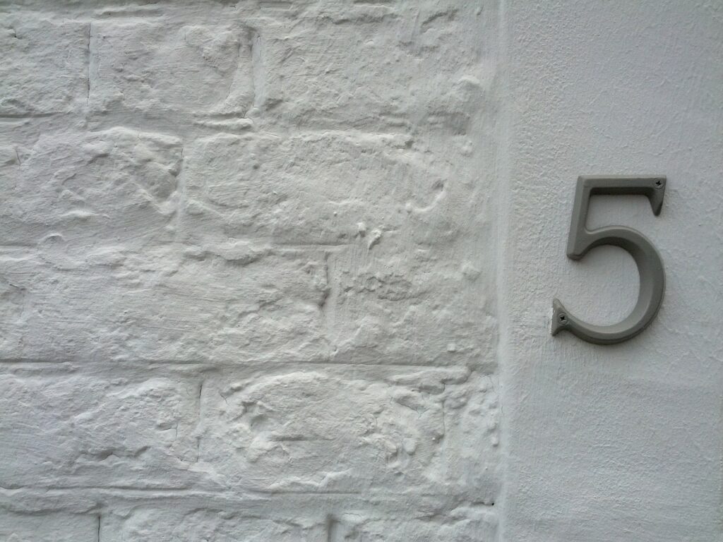Hausnummernschild mit Ziffer an einer Hauswand